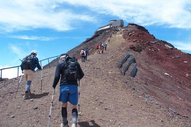 Hikers climbing the Mt. Fuji trail during the summer climbing season under clear skies.