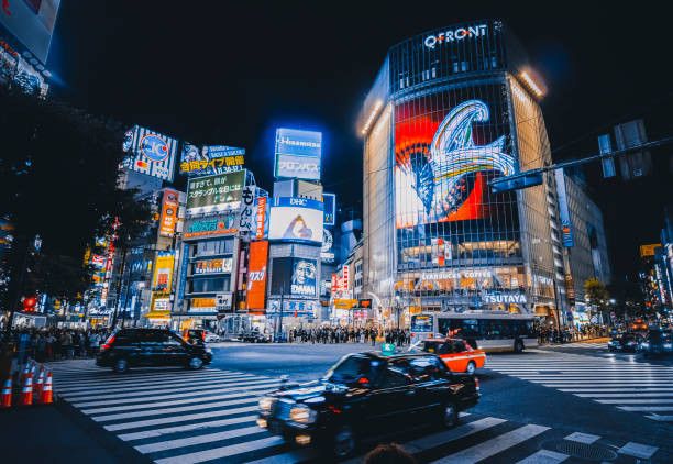 Shibuya Crossing at night with bright neon lights and crowds in Tokyo.