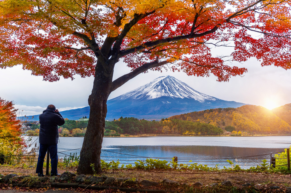 Person taking a photo of Mount Fuji, capturing Japan’s iconic mountain under a clear blue sky.